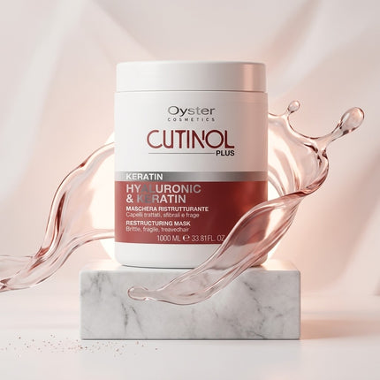 Oyster Cosmetics Cutinol Plus Keratin Hyaluionic & Keratin Restructuring Mask in a white jar with a metallic silver lid, displayed on a white marble block with a pink liquid splash effect.